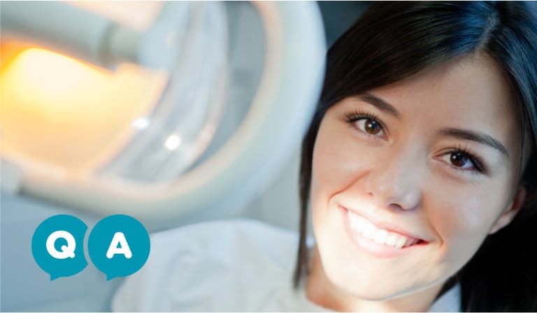 A woman smiles confidently while seated in a dental chair, showcasing a positive dental experience.